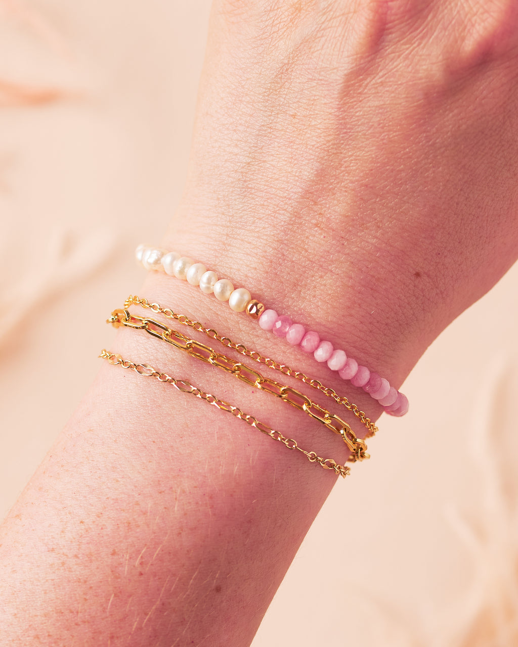 Model wearing the Balance Bracelet with freshwater pearls and pink jade, layered with the aria bracelet which features three delicate gold filled chains.