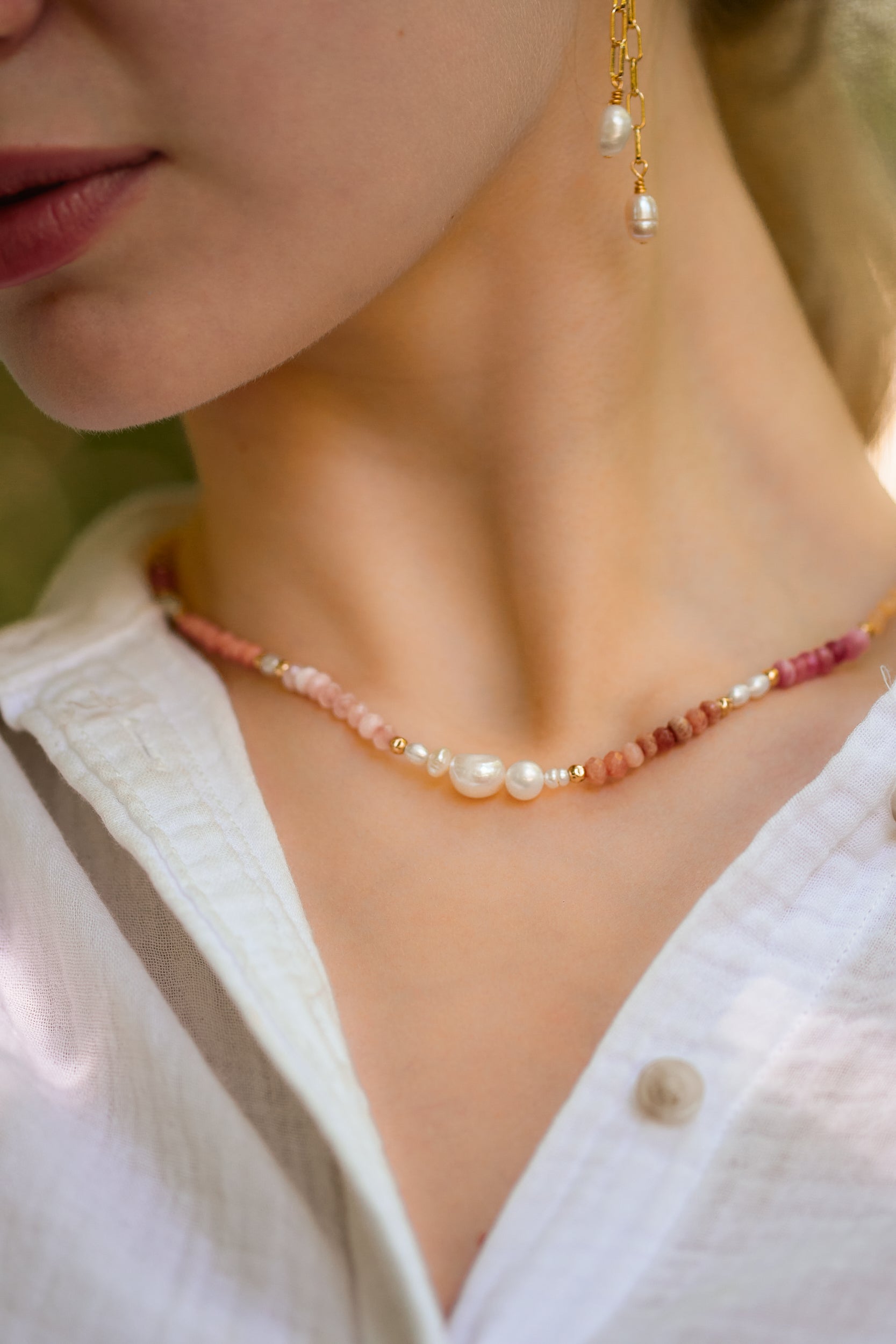 Model wearing soft pink ombré necklace with multi-colored stones and pearls styled with a blouse