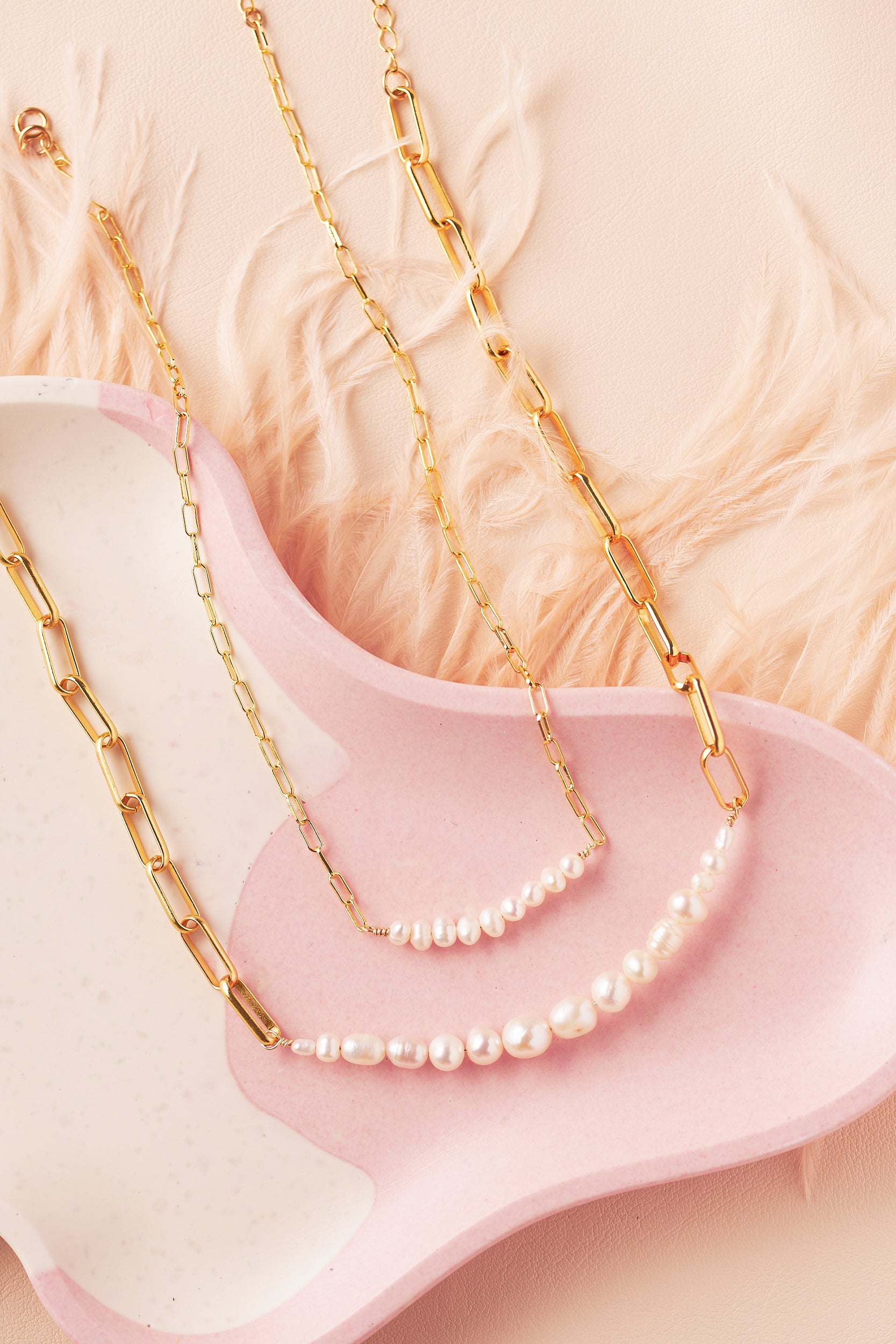delicate and bold pearl necklaces with gold filled paperclip chains on pink tray 
