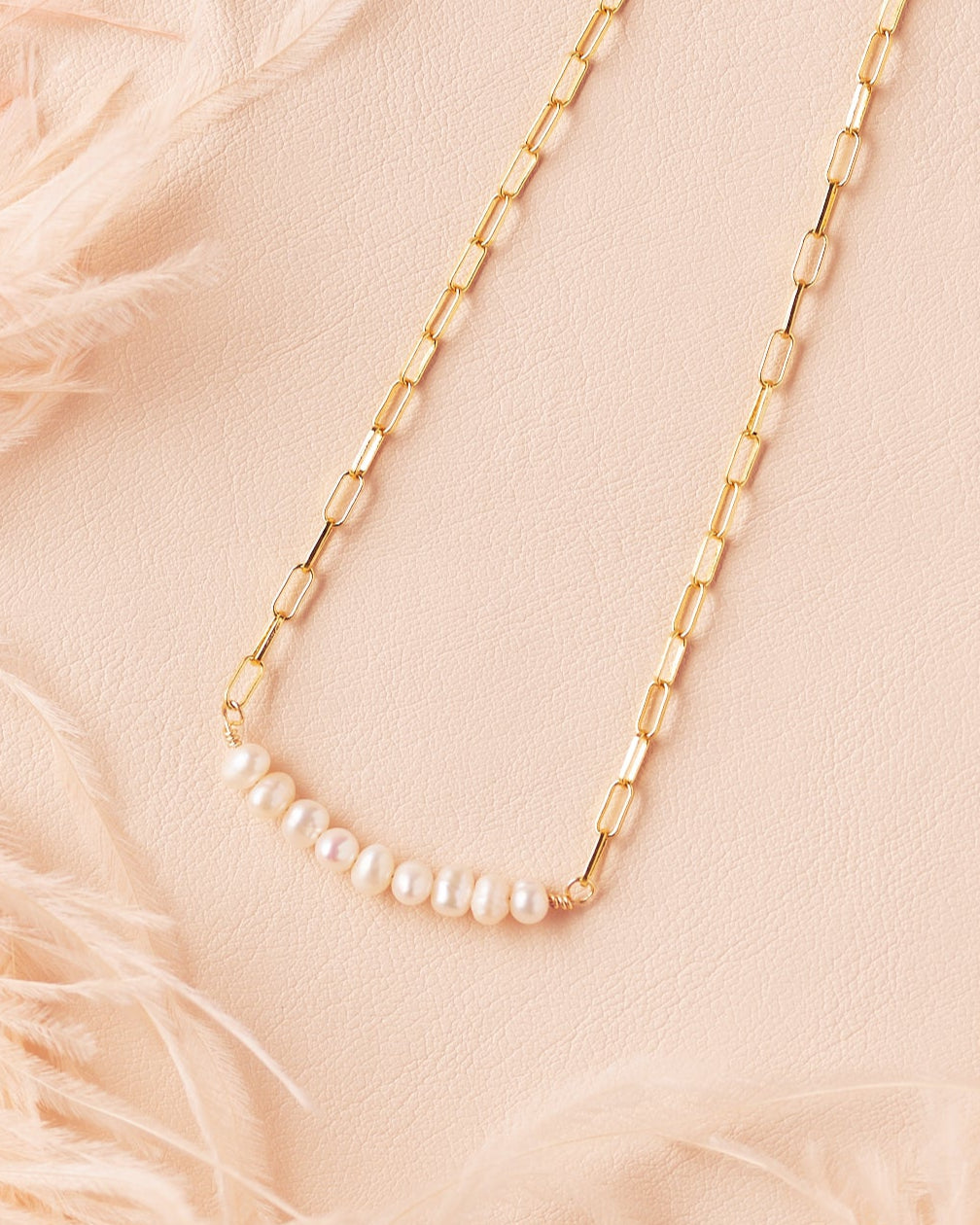 delicate pearl and gold filled paperclip necklace with pearls displayed flat on cream backdrop