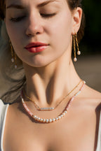 woman wearing 2 necklaces, one biwa pearl and delicate gold fill chain, one medium freshwater pearls, pink jade semiprecious beads and gold accents