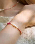 Close-up of a wrist wearing a bracelet with pink, cinnamon and terracotta semiprecious stones and pearls on a woman
