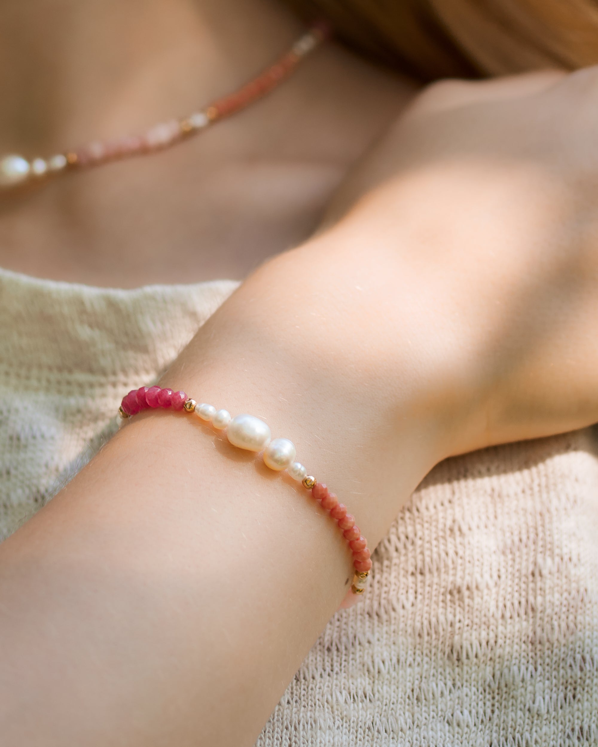 Close-up of a wrist wearing a bracelet with pink, cinnamon and terracotta semiprecious stones and pearls on a woman