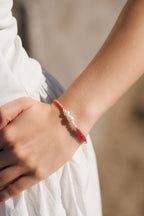 Close-up of a wrist wearing a bracelet with berry and terracotta semiprecious stones and freshwater pearls with gold fill accent beads.