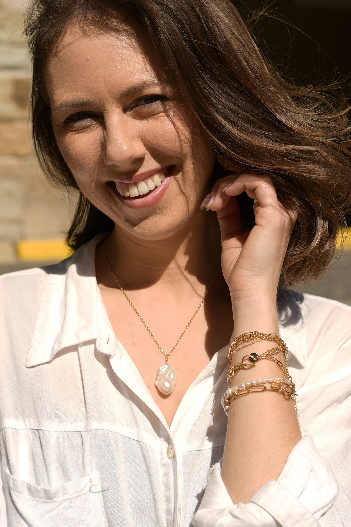 Aura Necklace worn with a white shirt and stacked gold bracelets